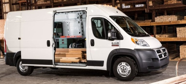 White cargo van with open sliding door revealing wooden planks inside, parked in a warehouse.