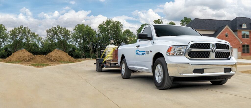 White pickup truck with Halson Construction branding towing a trailer on a neighborhood street.