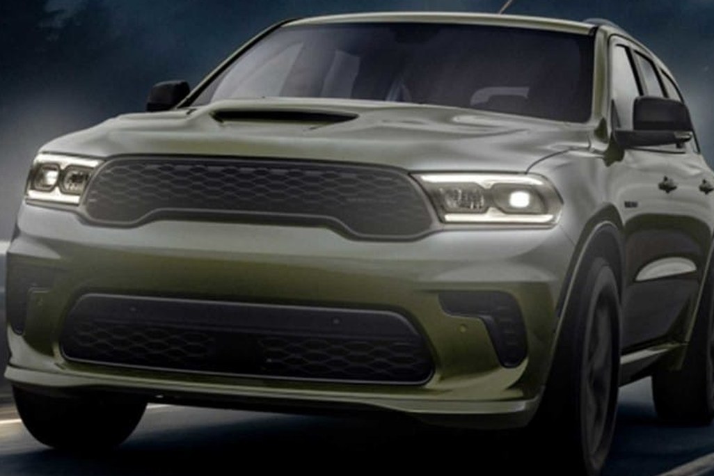 Green SUV driving at night with headlights on, showcasing a bold front grille design.