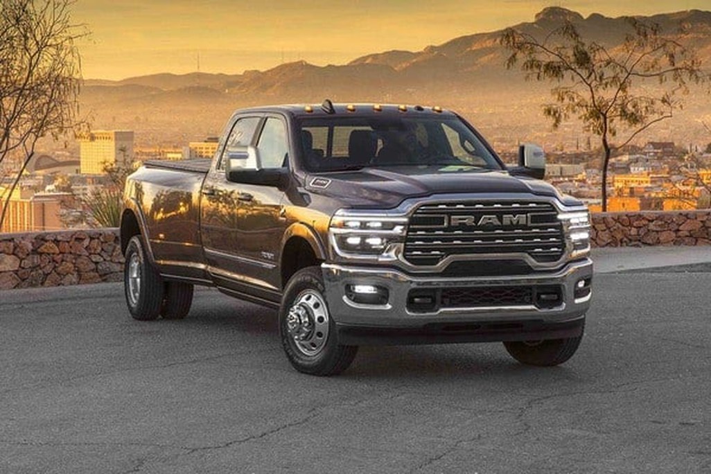 Ram 3500 dually pickup truck parked at sunset above a city, mountains in the background.