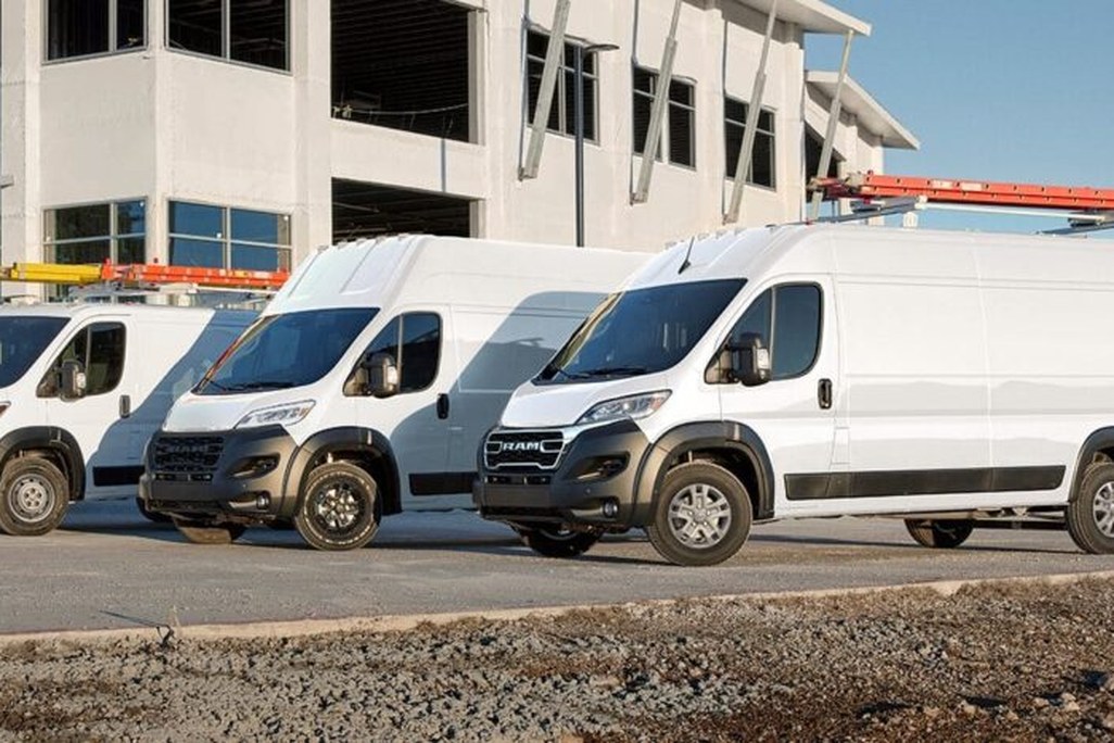 White commercial vans parked in front of a construction site under blue sky.