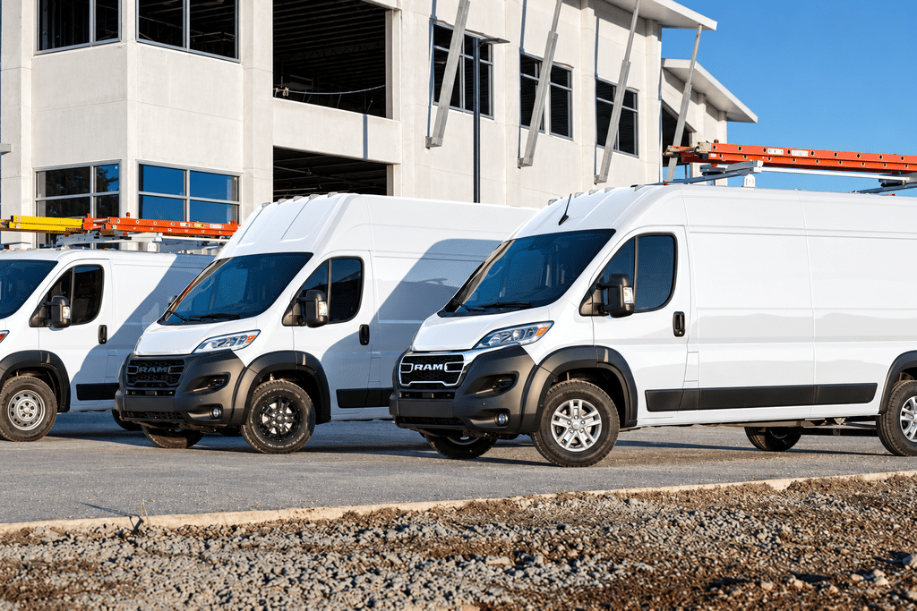 White delivery vans parked in front of a modern building under construction.